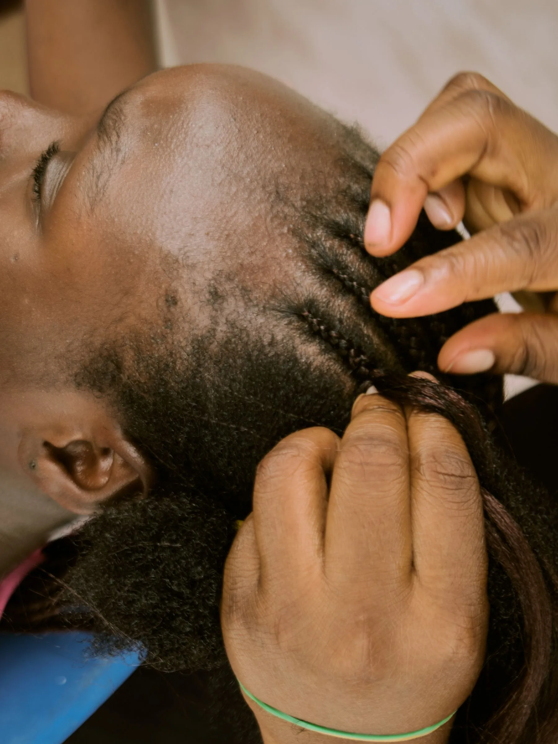Hands carefully braiding hair during practical training